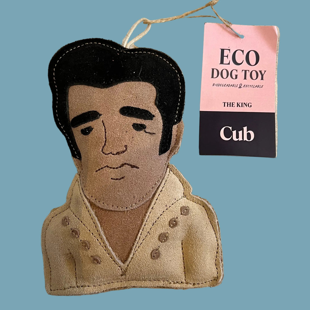 A handmade felt dog toy shaped like Elvis Presley's bust, featuring black hair and a beige jacket, with a pink and black hangtag reading 'ECO DOG TOY' and 'Cub'.